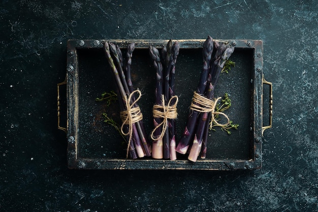 Raw Organic Purple Asparagus on a black stone background Healthy food Top view free copy space