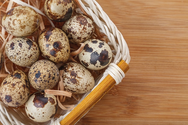 Foto uova di quaglia organiche crude nel canestro di bambù sulla tavola di legno.