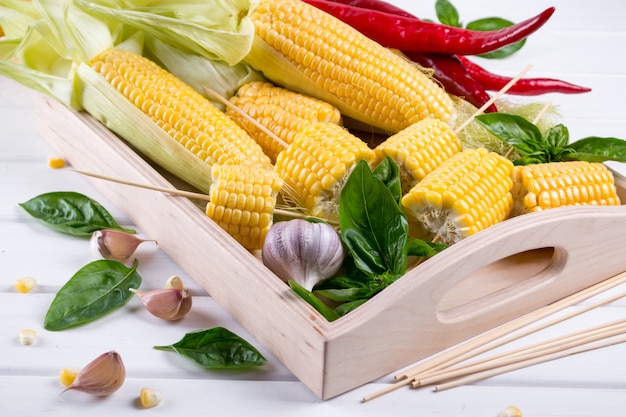 raw organic yellow corn on the cob ready to grill with hot chili pepper garlic and herbs. mexican corn. ideas for barbecue and grill parties