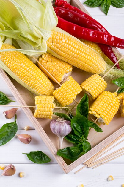 raw organic yellow corn on the cob ready to grill with hot chili pepper garlic and herbs. mexican corn. ideas for barbecue and grill parties
