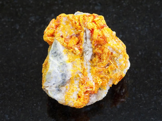 Raw Orpiment crystals on dolomite stone on dark