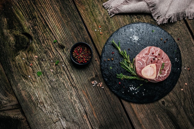 暗い背景にハーブとスパイスを入れた生のオッソブコステーキ大理石の肉、テキストトップビューのバナーメニューレシピの場所