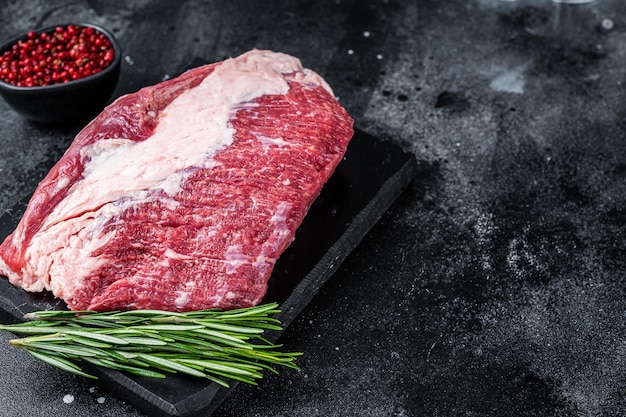 Raw outside Round roast beef meat cut on a marble board. Black background. Top view. Copy space.