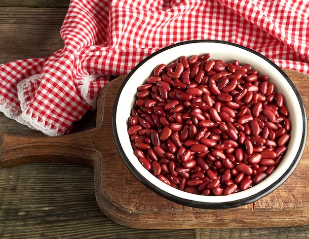 Raw oval red beans in a plate on a wooden table