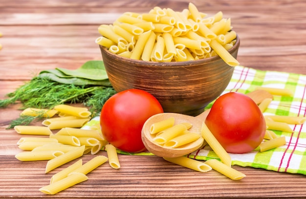 Raw pasta in bowl with ingredients for cooking