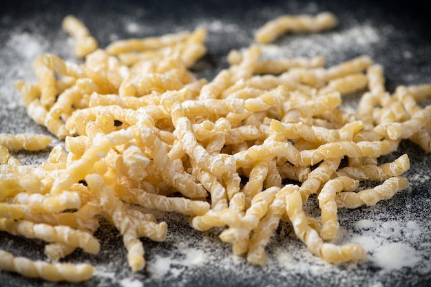 Raw pasta busiate on wooden table