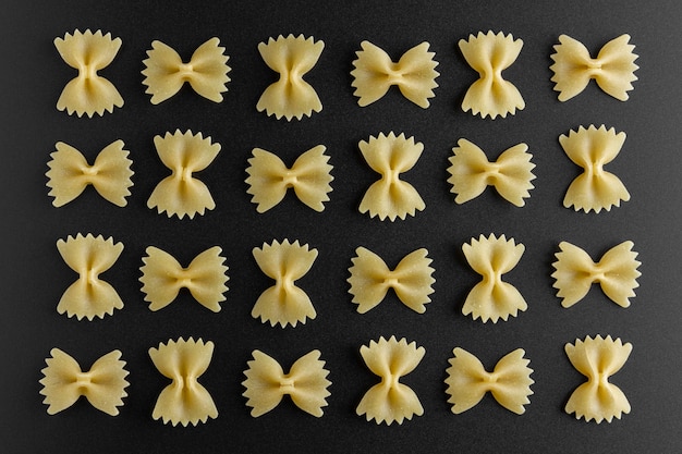 Raw pasta farfalle pattern on black background