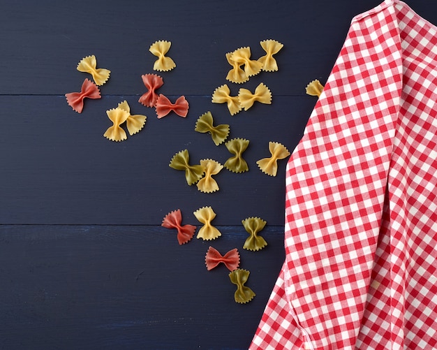 Raw pasta in the form of bows with checkered towel