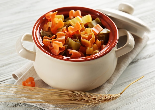 Raw pasta in pan on wooden background