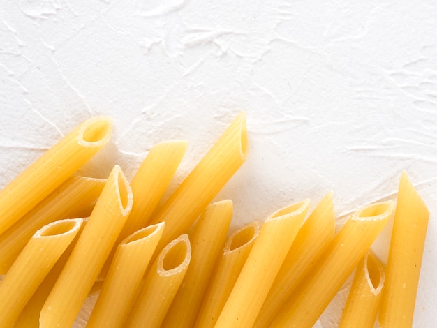 Raw pasta penne on white background