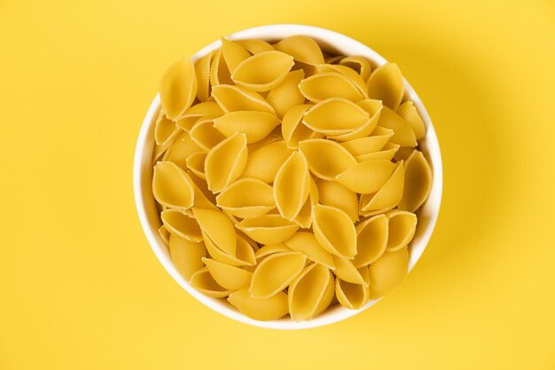 Raw pasta in a plate isolated on yellow background