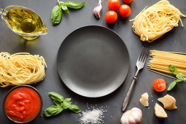 Raw pasta, spaghetti, tomatoes, basil, parmesan for cooking Mediterranean dishes.