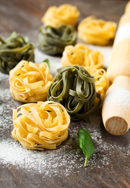 Raw pasta Tagliatelle Paglia e Fieno on a dark background
