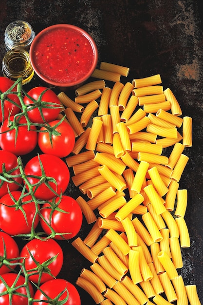 Raw pasta and tomatoes on the branch. Concept cooking pasta with tomato sauce.