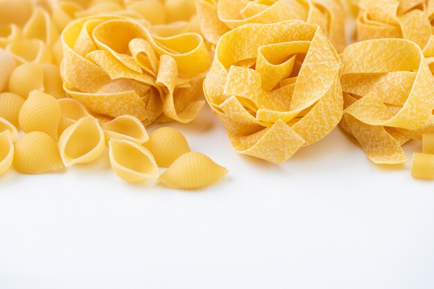 Raw pasta on white surface close up