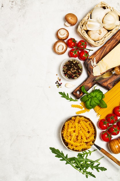 Raw pasta with tomatoes and spices with a cutting board with cheese