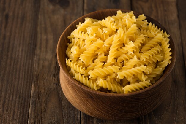 Raw pasta in wood plate on wood background