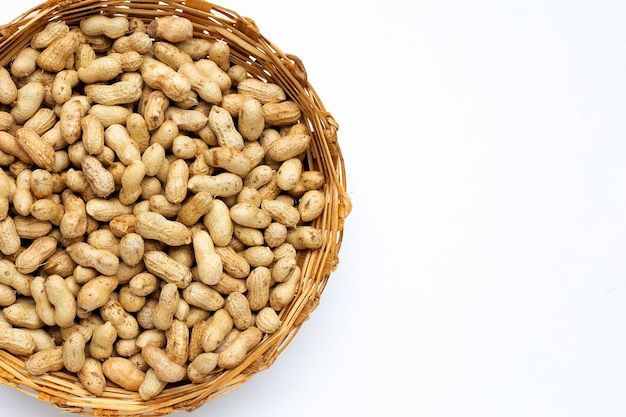 Raw peanuts in bamboo basket on white background.