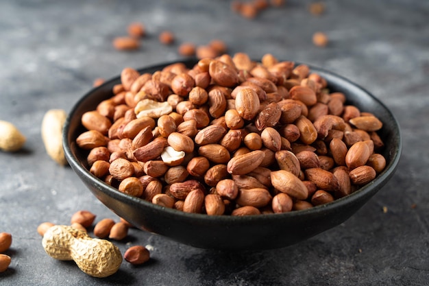 Raw Peanuts in wooden bowl on natural gray rustic desk.