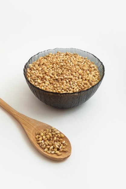 Raw pearl barley in a wooden spoon and in a plate