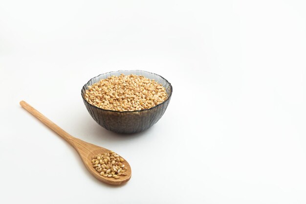 Raw pearl barley in a wooden spoon and in a plate