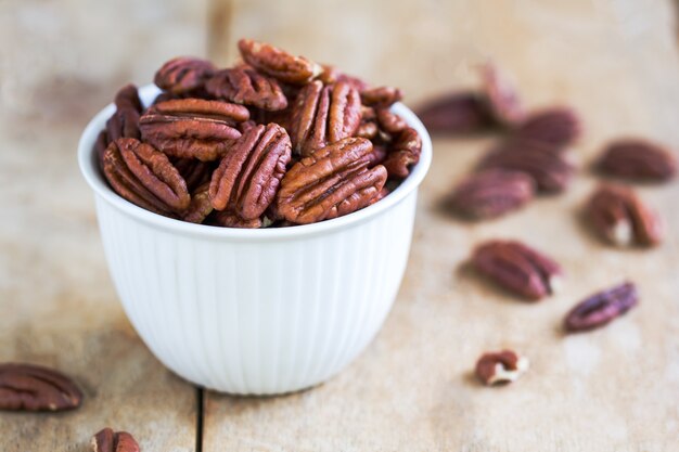 Raw Pecan in a white bowl on wooden board