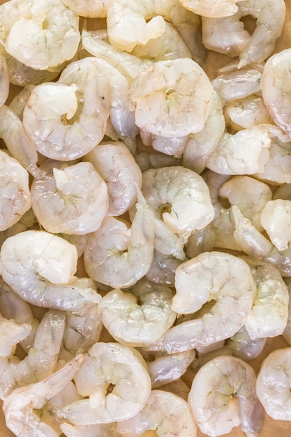 Raw peeled shrimp on a brown butcher paper.