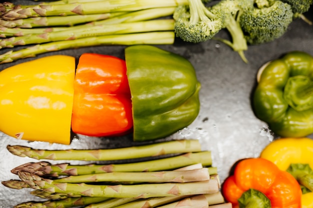 Raw peppers and green asparagus on metal tablet