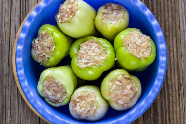 Raw peppers stuffed with meat on a wooden cutting board