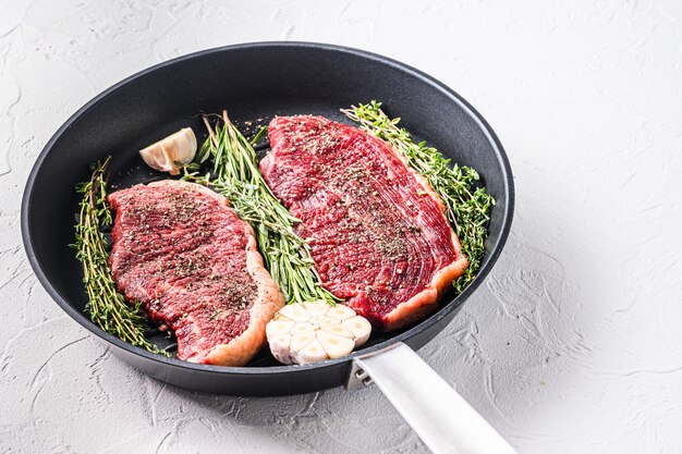 Raw picanha organic beef steaks ready for grill on pan with herbs and garlic.