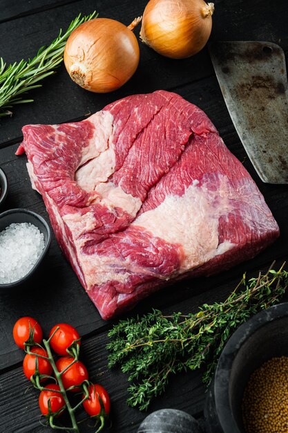 Raw piece of marble beef brisketwith ingredients for smoking making barbecue pastrami cure on black wooden table background