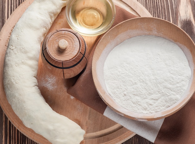 Raw pies and flour on wooden table