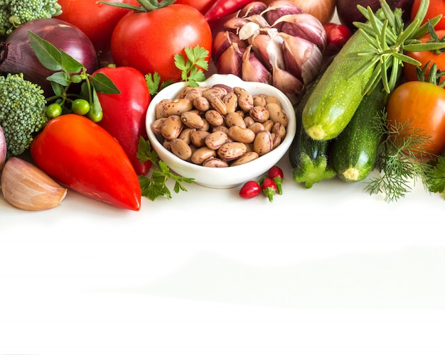 Raw pinto beans and vegetables border isolated on white close up