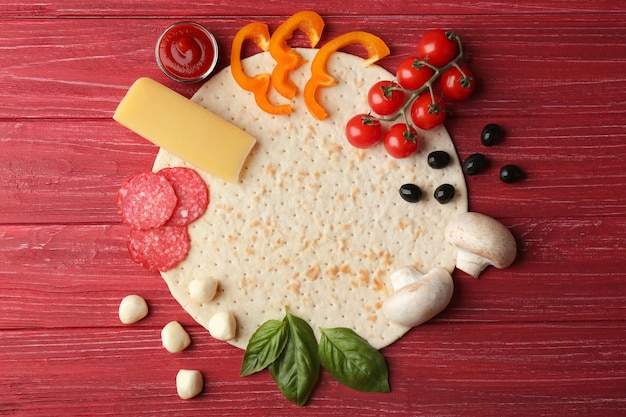 Raw pizza ingredients on wooden background top view