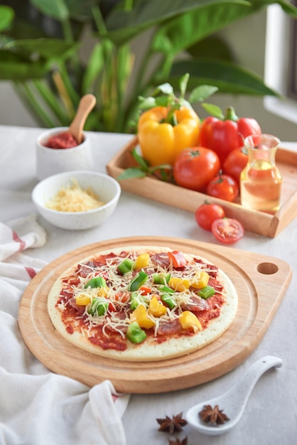 Raw pizza with ingredients in the background