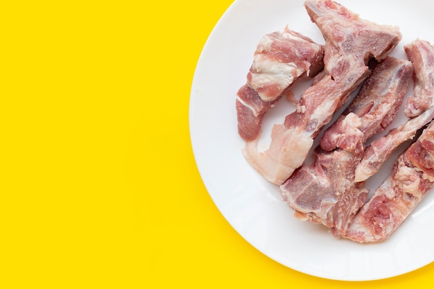 Raw pork bone in white plate on background.