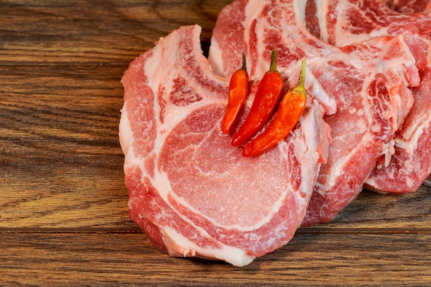 Raw pork chop steak with ingredients pepper, on a wooden cutting board 