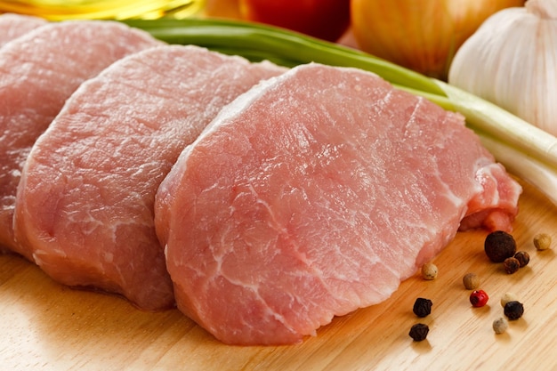 Photo raw pork chops on cutting board and vegetables