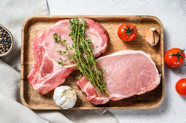 Raw pork cutlet. Organic meat steak. White background. Top view.