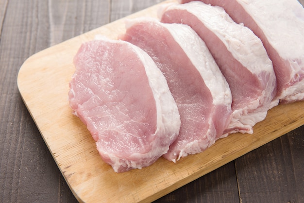 Photo raw pork on cutting board on wood