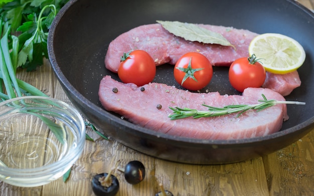 Raw pork on a frying pan on a rustic table.