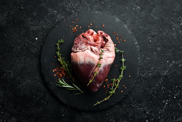 Raw pork heart is ready to cook with spices and herbs Meat On a black background