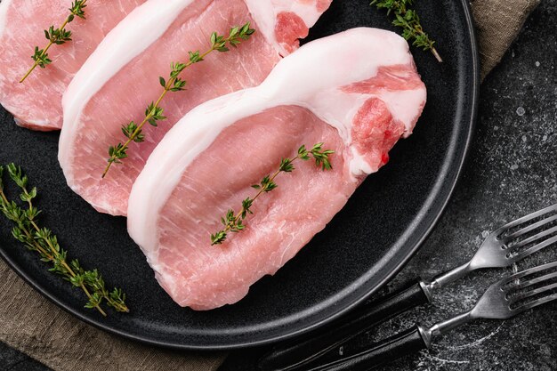 Raw Pork Loin chops set, on black dark stone table background, top view flat lay