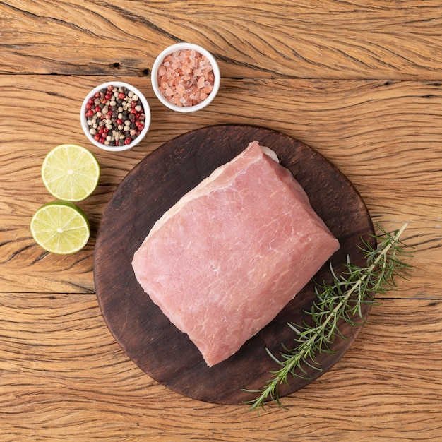 Raw pork loin meat over wooden board with seasonings.