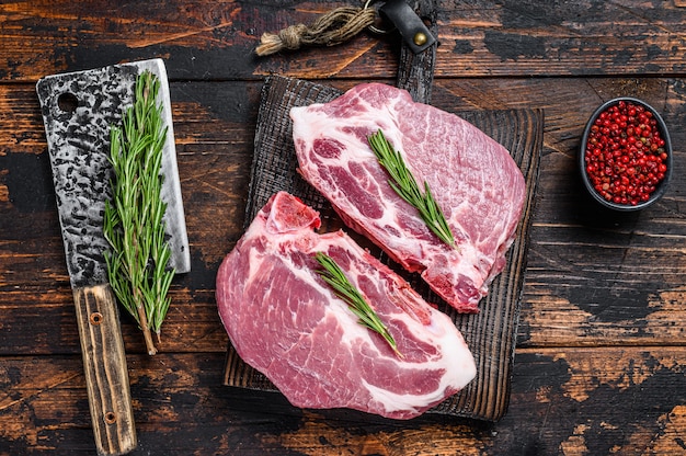 Raw pork loin steaks with herbs on a cutting board with meat cleaver