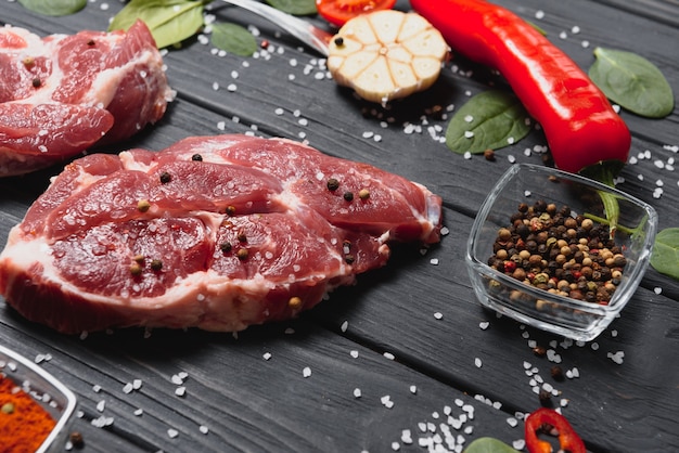 Raw pork meat with spices and vegetables on wooden table