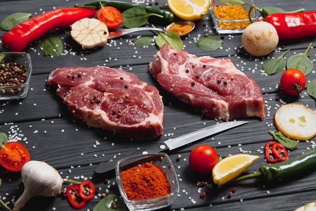 Raw pork meat with spices and vegetables on wooden table