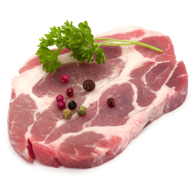 Raw pork neck chop meat with parsley herb leaves and peppercorn spices garnish isolated on white background cutout