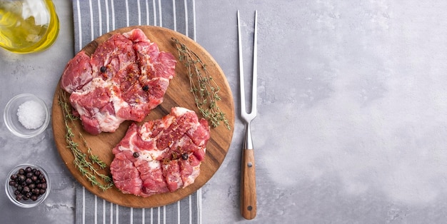 Photo raw pork neck pieces with spices on a wooden board top view space for text