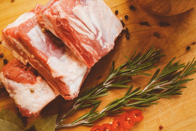 Raw pork rib chops on cut board with rosemary pepper garlic and bay leaf vintage photo processing